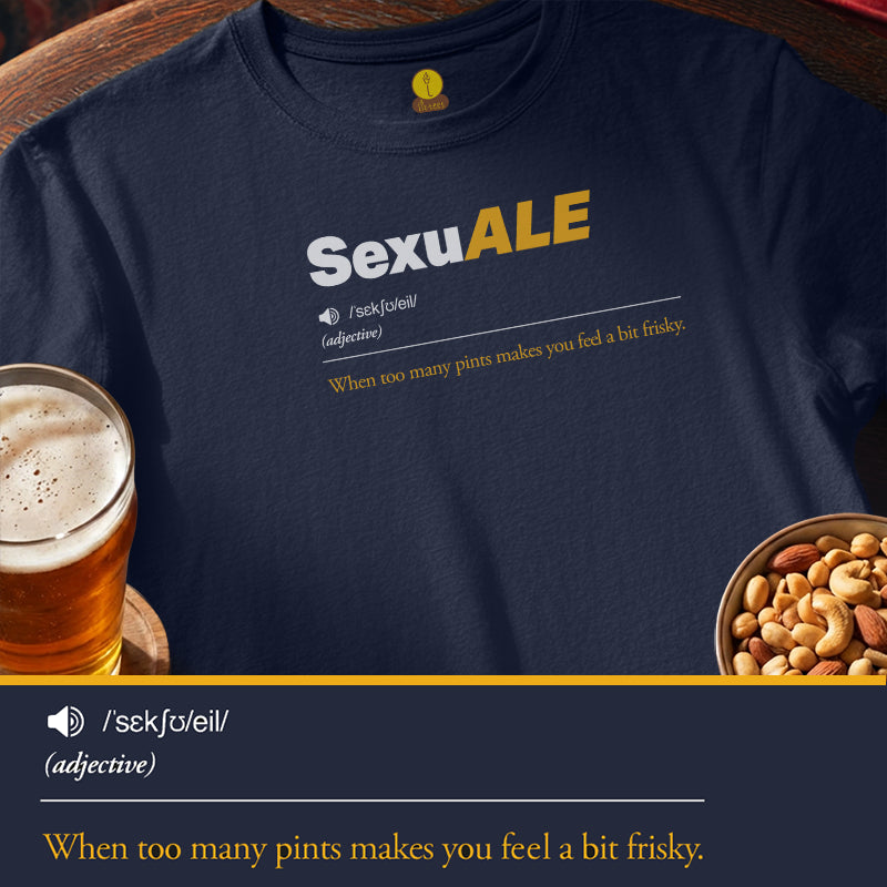 A navy blue t-shirt with a custom dictionary-style definition print for 'SexuALE' on the chest, styled in a flat-lay with a glass of beer and a bowl of nuts on a wooden surface.