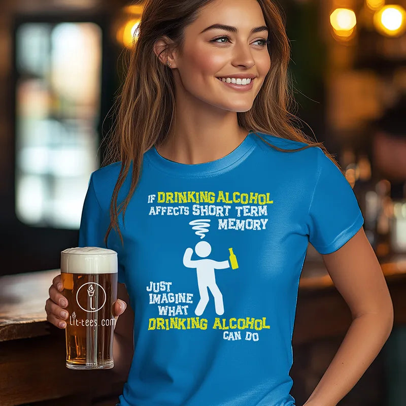 Woman holding a beer in a bar wearing a blue tee shirt with a cartoon character and humorous text saying 'If drinking alcohol affects short term memory just imagine what drinking alcohol can do' 