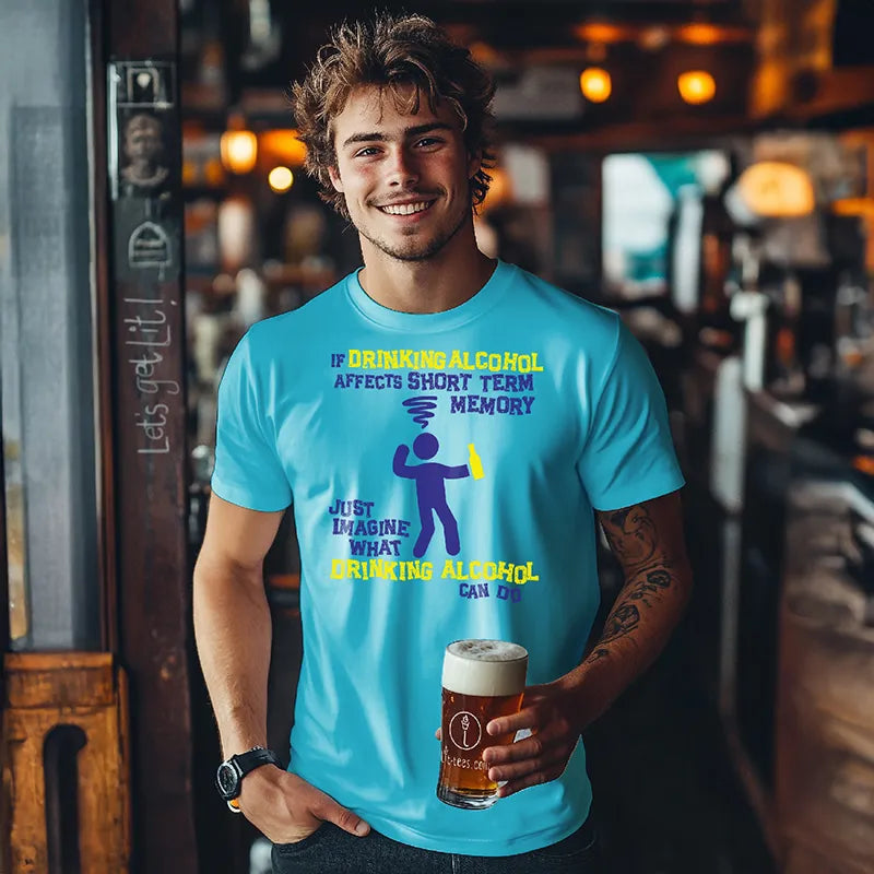 Man holding a beer in a bar wearing a blue tee shirt with a graphic character and humorous text saying 'If drinking alcohol affects short term memory just imagine what drinking alcohol can do' 
