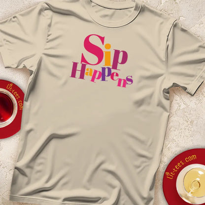 Sand t-shirt with 'Sip Happens' text, placed on a textured surface with teacups.
