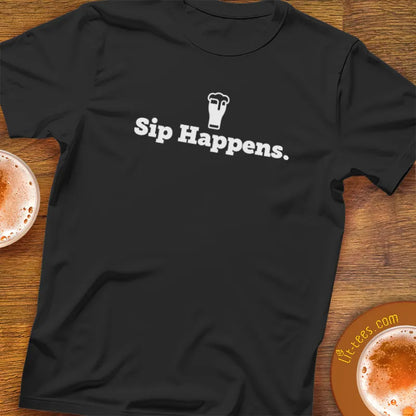 Black t-shirt with 'Sip Happens.' text on a wooden surface with drinks.