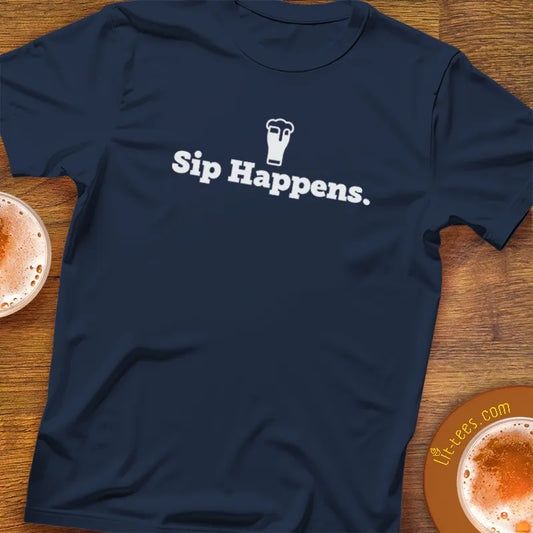 Navy blue t-shirt with 'Sip Happens.' text on a wooden surface with coffee cups.