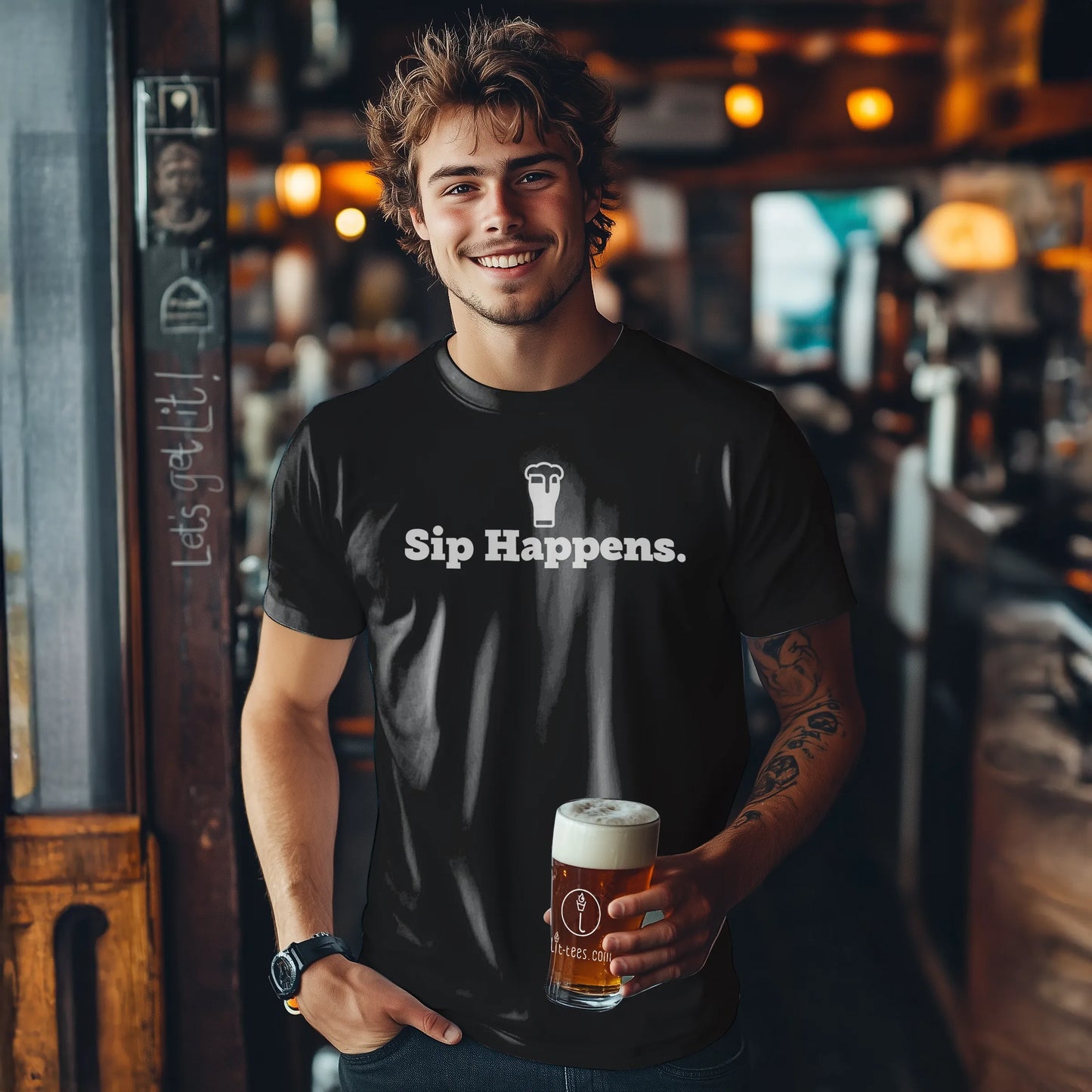 Man holding a beer in a bar wearing a black t-shirt with 'Sip Happens.' text.