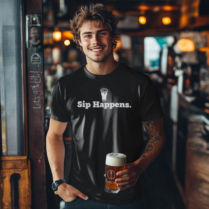 Man holding a beer in a bar wearing a black t-shirt with 'Sip Happens.' text.