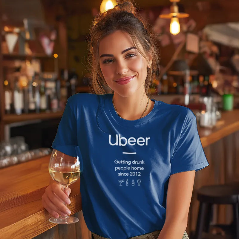 Woman in a bar wearing a blue 'Ubeer' t-shirt holding a glass of wine.