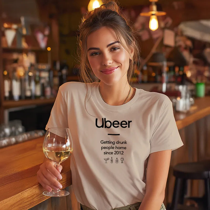 Woman in a bar wearing a t-shirt with 'Ubeer' text holding a glass of wine.