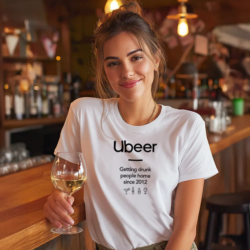Woman in a bar wearing a white t-shirt with 'Ubeer' text, holding a glass of wine.
