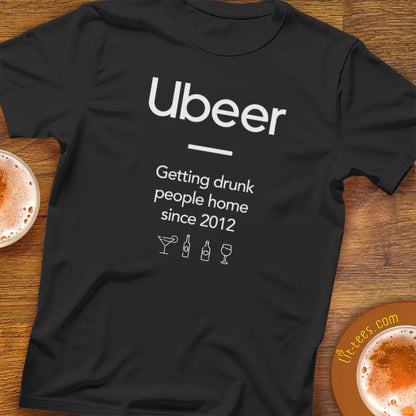 Black t-shirt with 'Ubeer' text and graphics on a wooden surface with drinks.