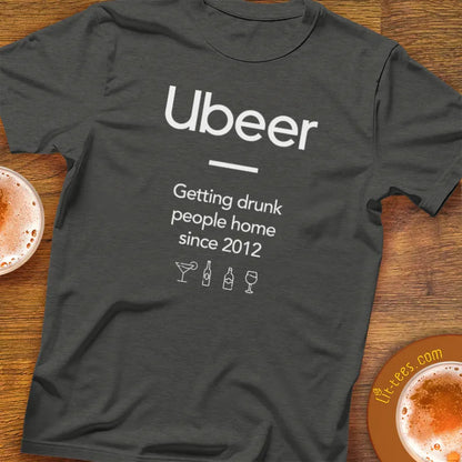 Gray t-shirt with 'Ubeer' text and graphics on a wooden surface with drinks.