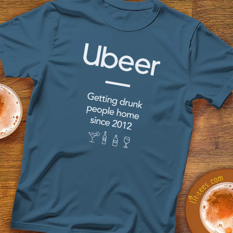 Blue t-shirt with 'Ubeer' text and graphics on a wooden surface with drinks.