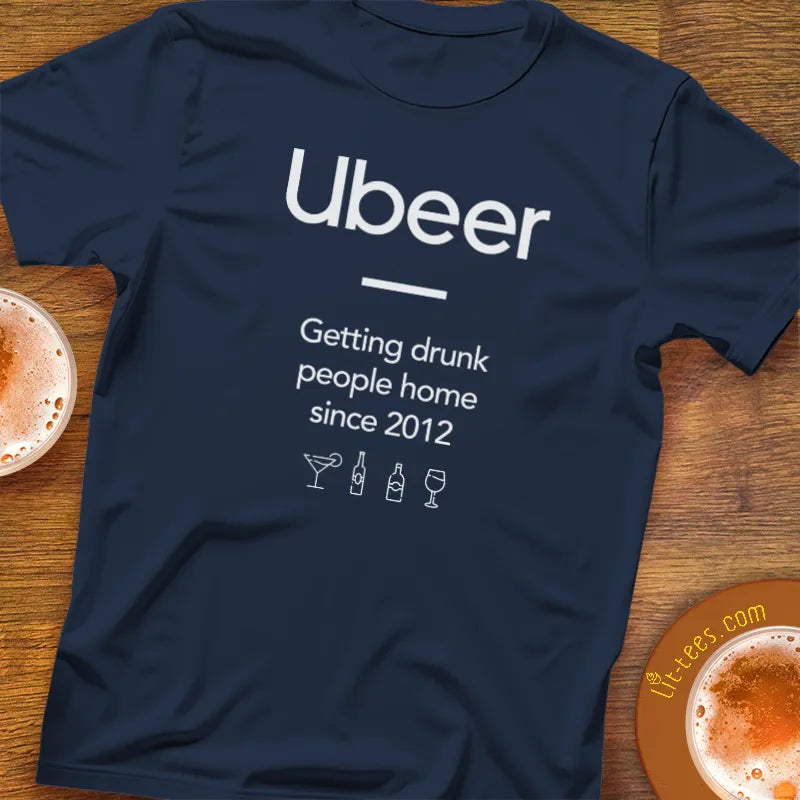 Navy blue t-shirt with 'Ubeer' text and graphics on a wooden surface with drinks.