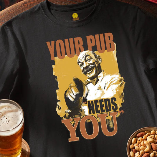 Black t-shirt with graphic of a man and text 'Your pub needs you' on a wooden surface with a glass of beer and bowl of nuts.